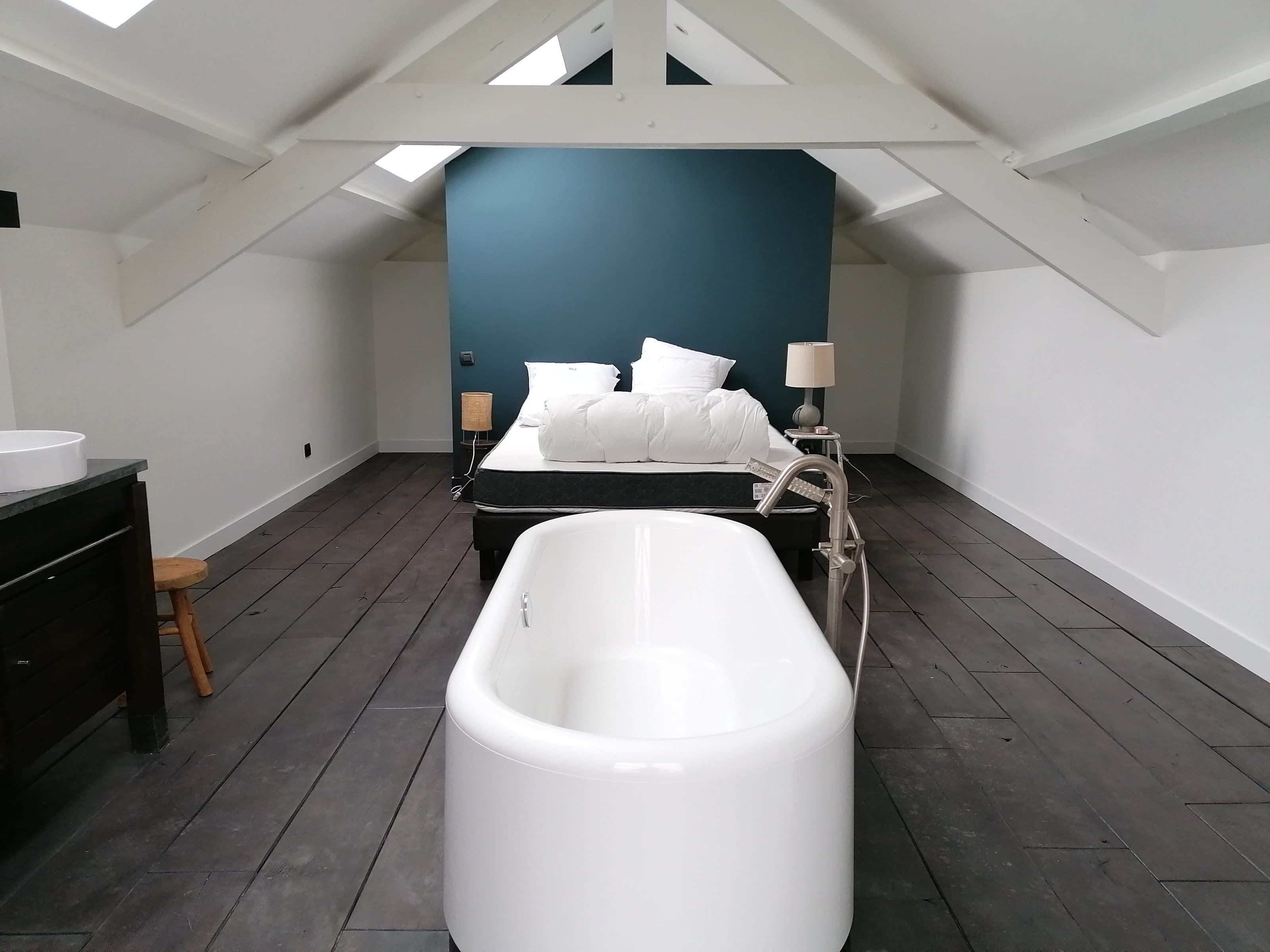 Chambre sous combles avec mur bleu canard et baignoire îlot