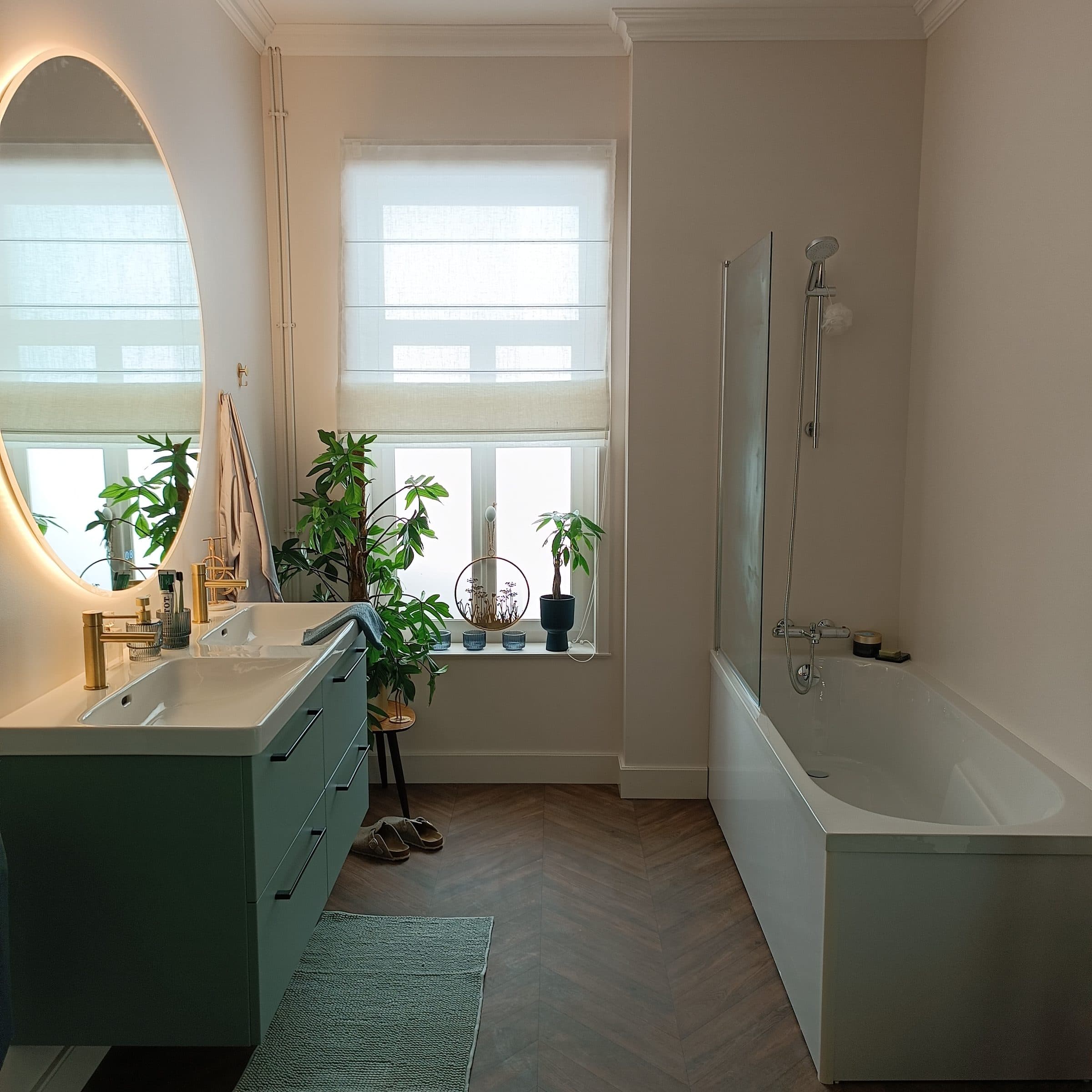 Salle de bain élégante : meuble vert, miroir doré et parquet en chevrons
