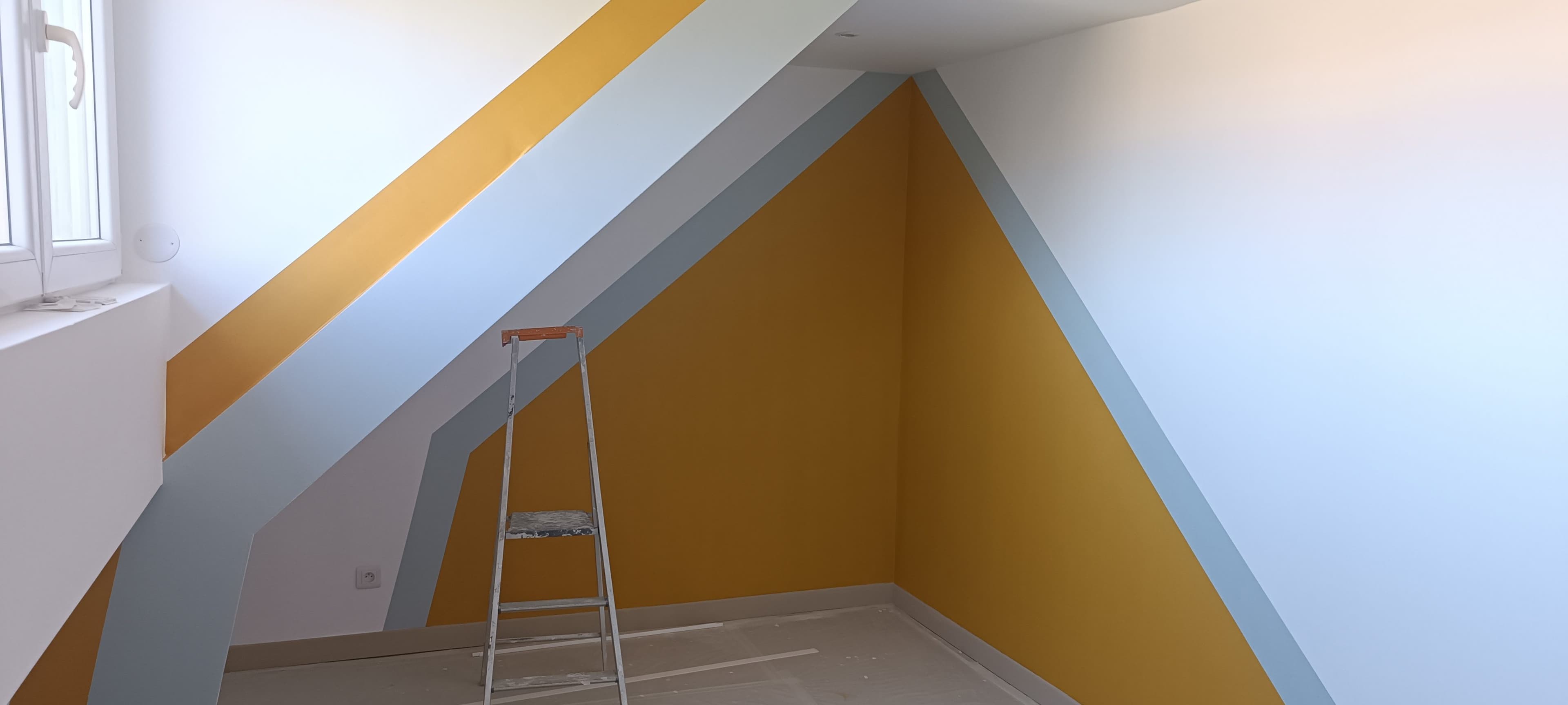 Chambre d'enfant sous pente avec aplats géométriques jaune moutarde et bleu-gris
