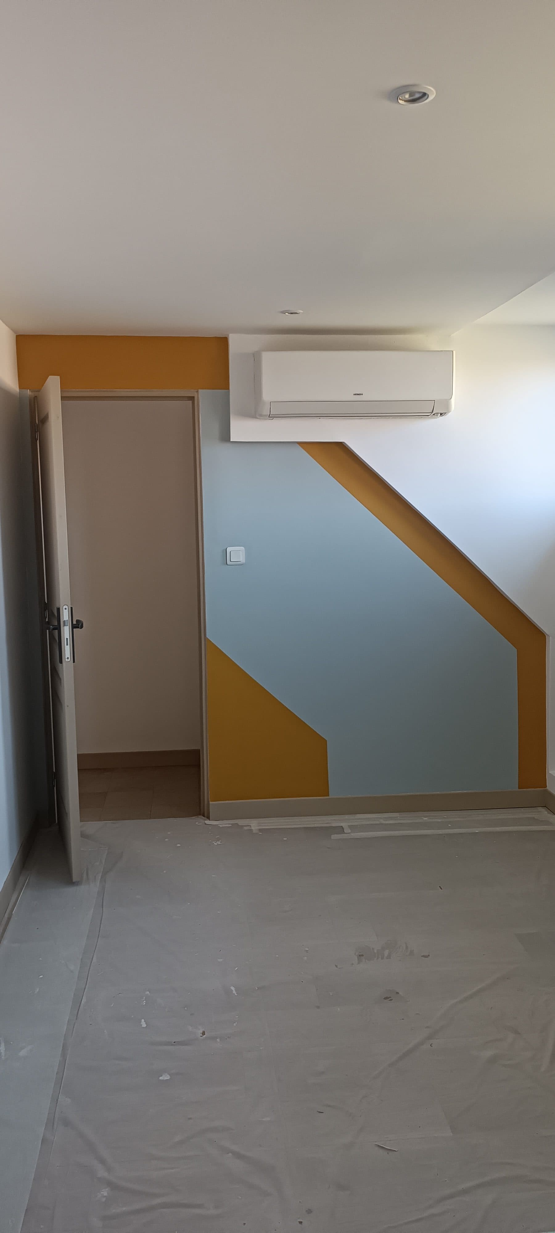 Mur côté porte avec aplat bleu-gris et triangles jaune moutarde
