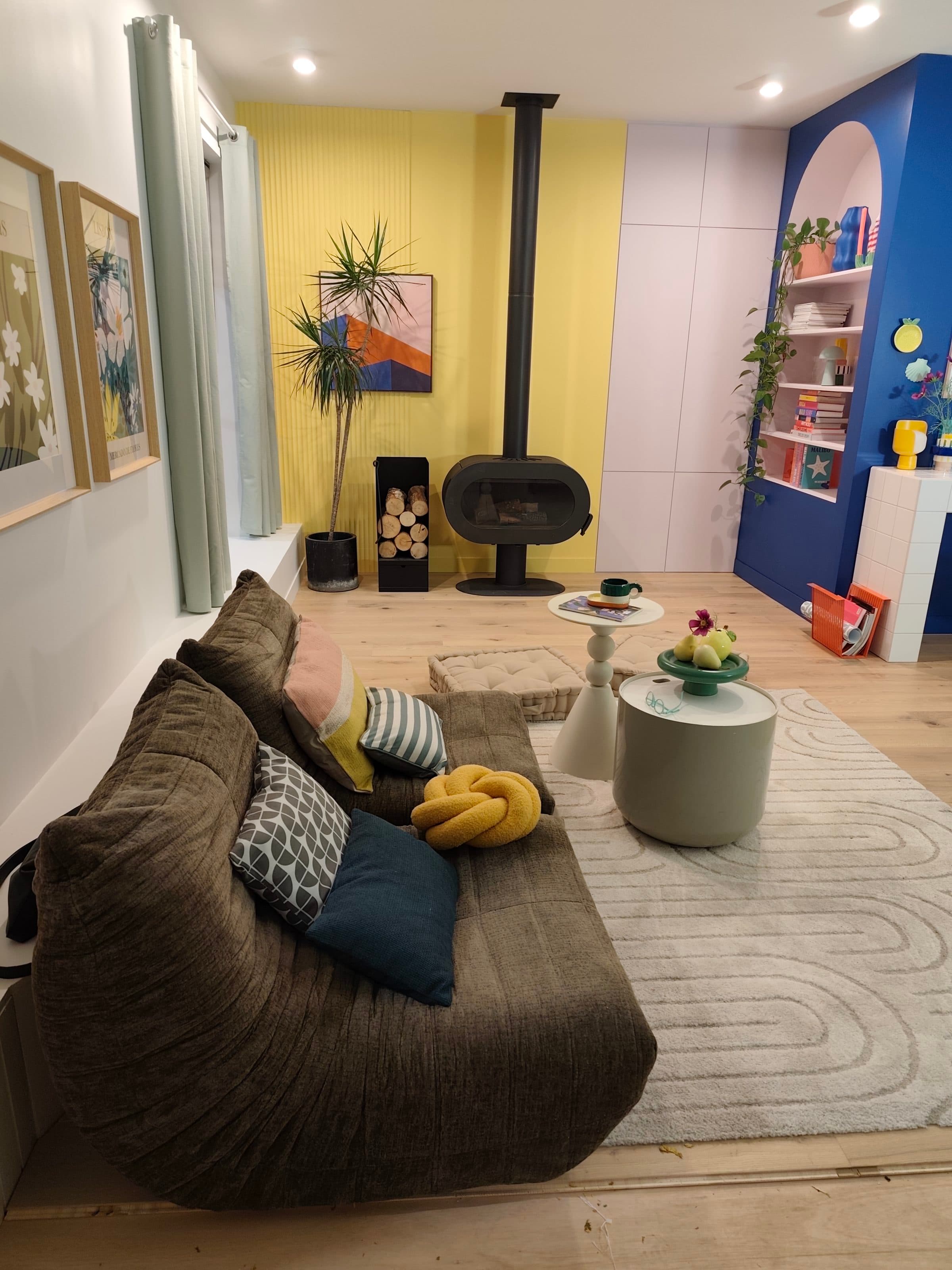 Séjour coloré avec mur jaune, arche bleue et rangements rose poudré